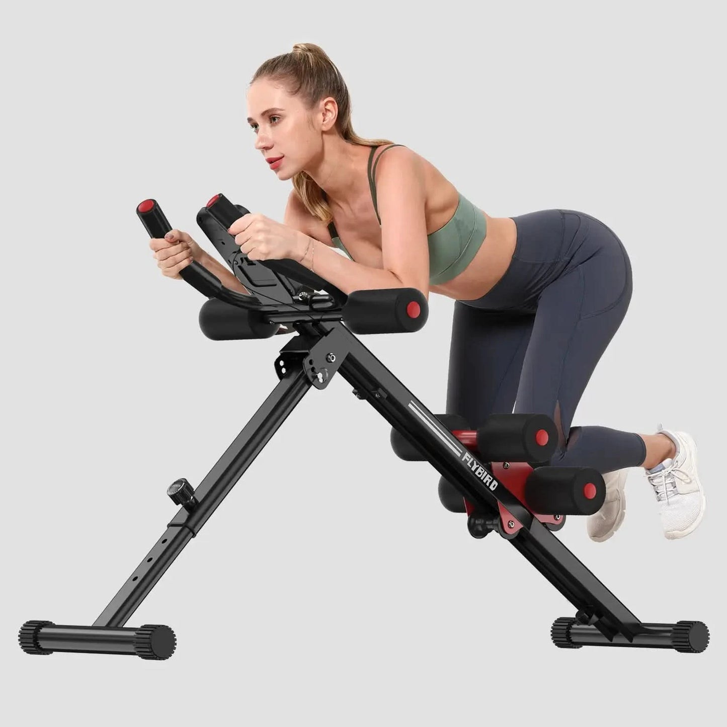 Woman using a black and red exercise machine on a gray background
