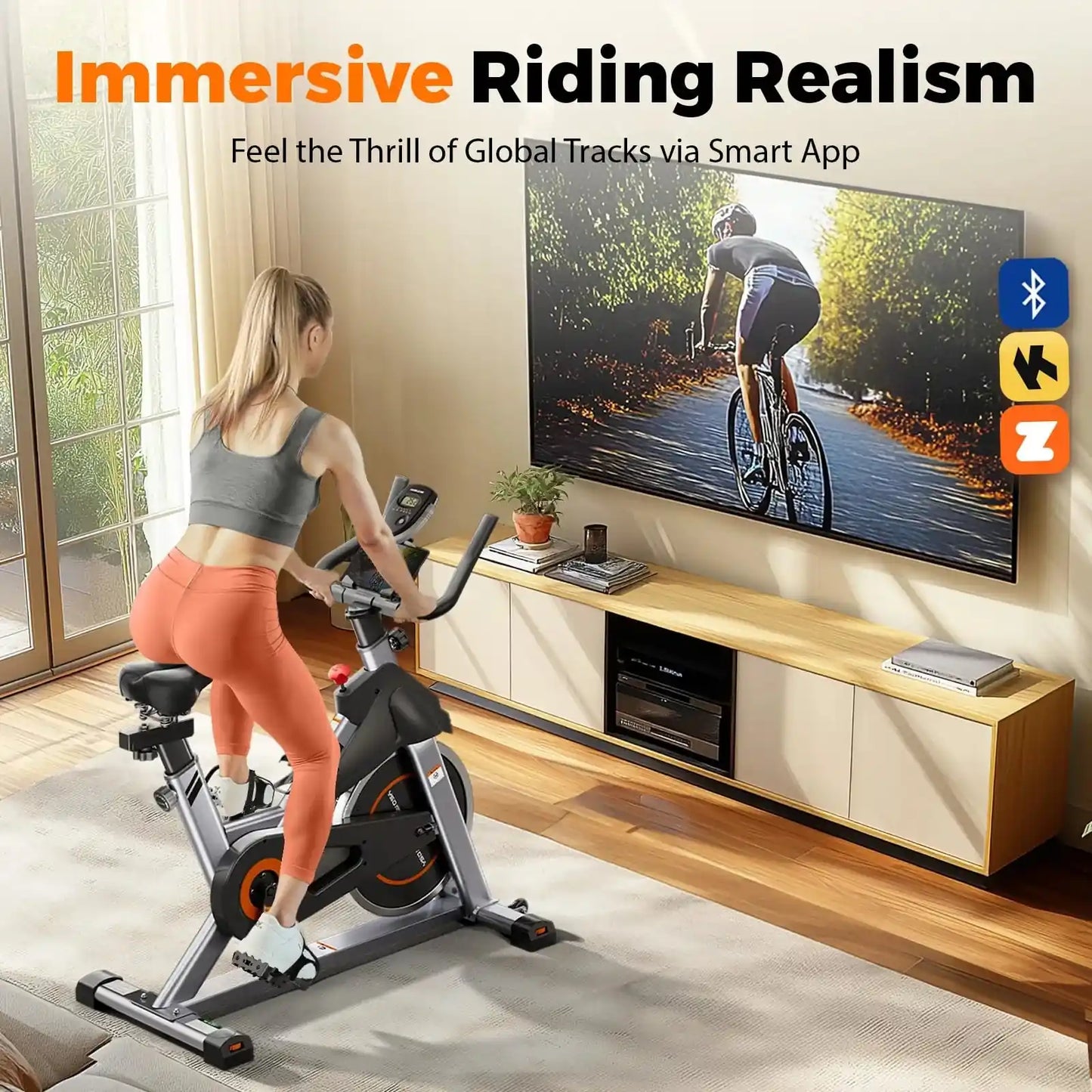 Woman exercising on a stationary bike in a living room with a TV displaying cycling content.