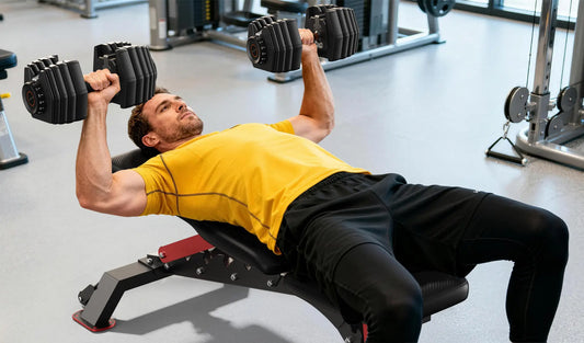 A person lies on a flat bench and does dumbbell bench presses.