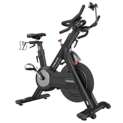 The FED Fitness Yosuda series EB3C indoor exercise bike features a black frame, a silver flywheel cover, and an orange resistance knob.