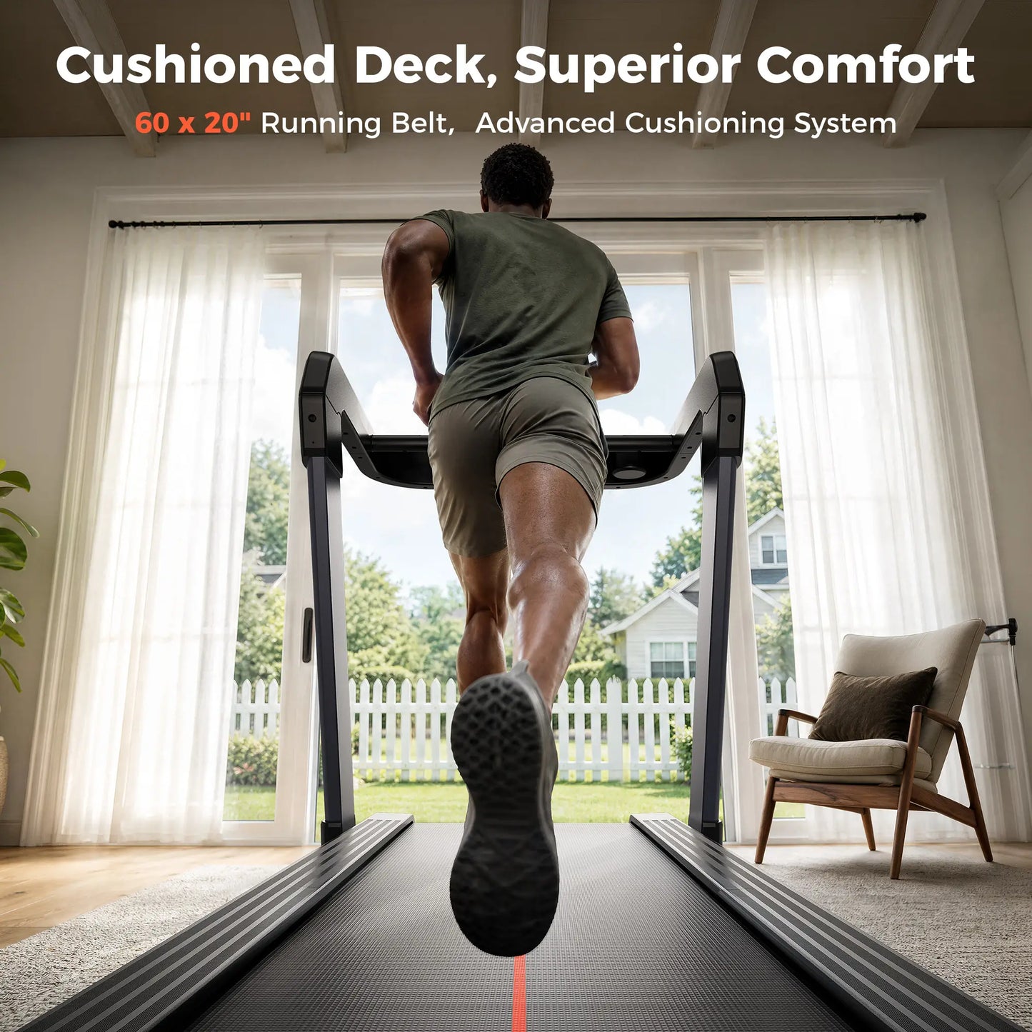 A man runs on a treadmill from behind in a bright home interior, with large windows, curtains, a chair, and outdoor greenery visible. White and orange text at the top reads: 'Cushioned Deck, Superior Comfort' and '60 x 20" Running Belt, Advanced Cushioning System.
