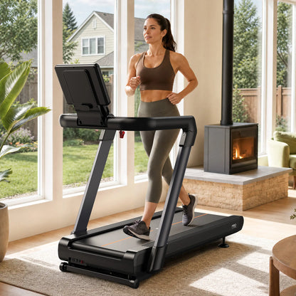 A woman jogging on a black treadmill in a bright, modern room with large windows, a wood-burning fireplace, and a visible 'Tread' brand mark on the treadmill.