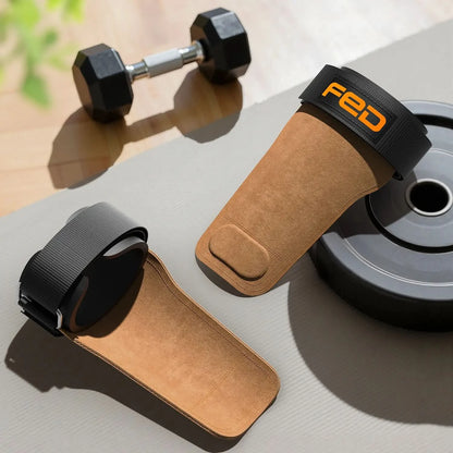 Pair of brown and black wrist wraps with 'FED' branding on a gray surface with dumbbells and a weight plate in the background.