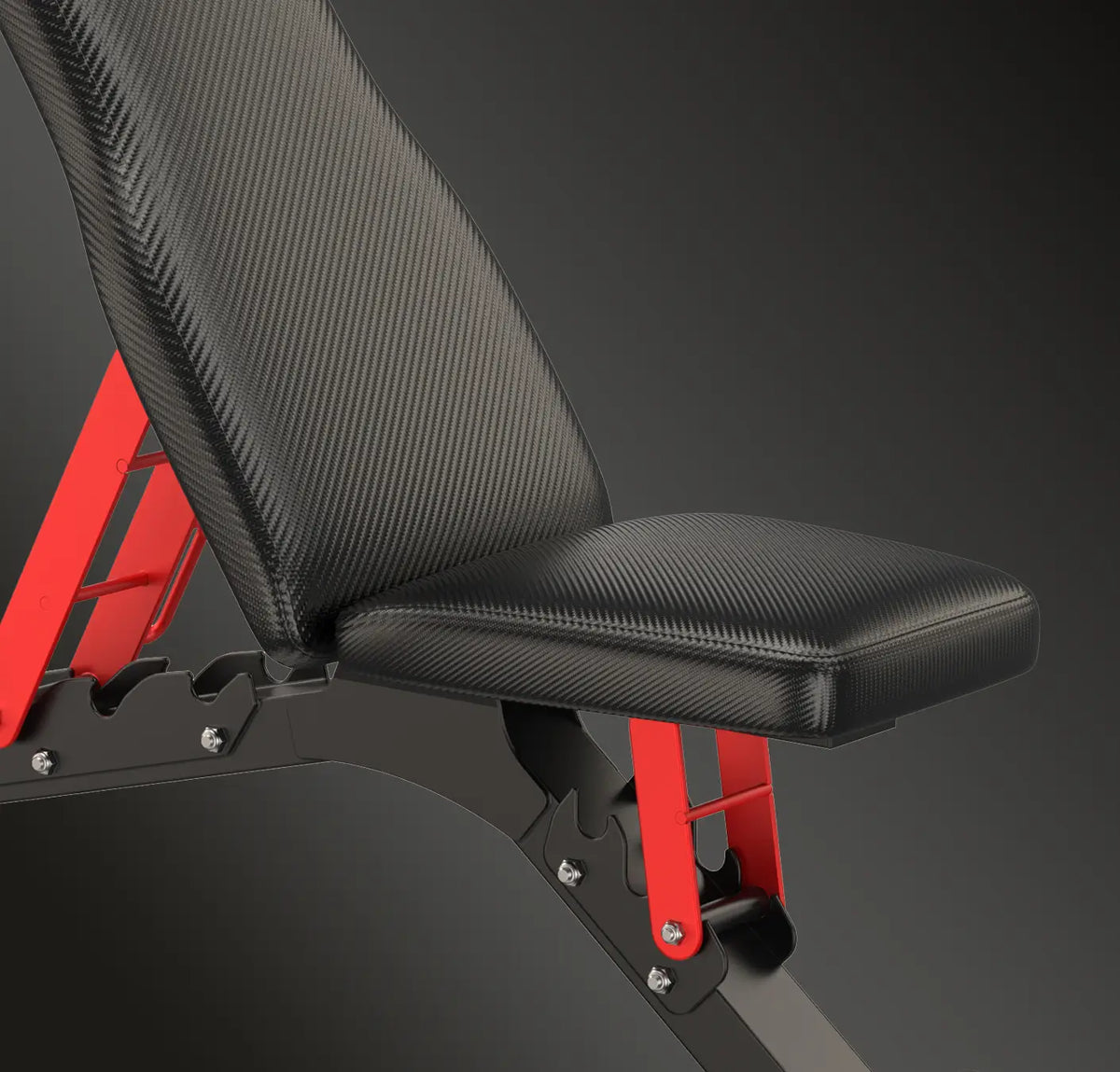 Close-up of a weight bench with a black textured fabric seat and backrest, supported by a black frame with bright red metal brackets, set against a dark gray background.