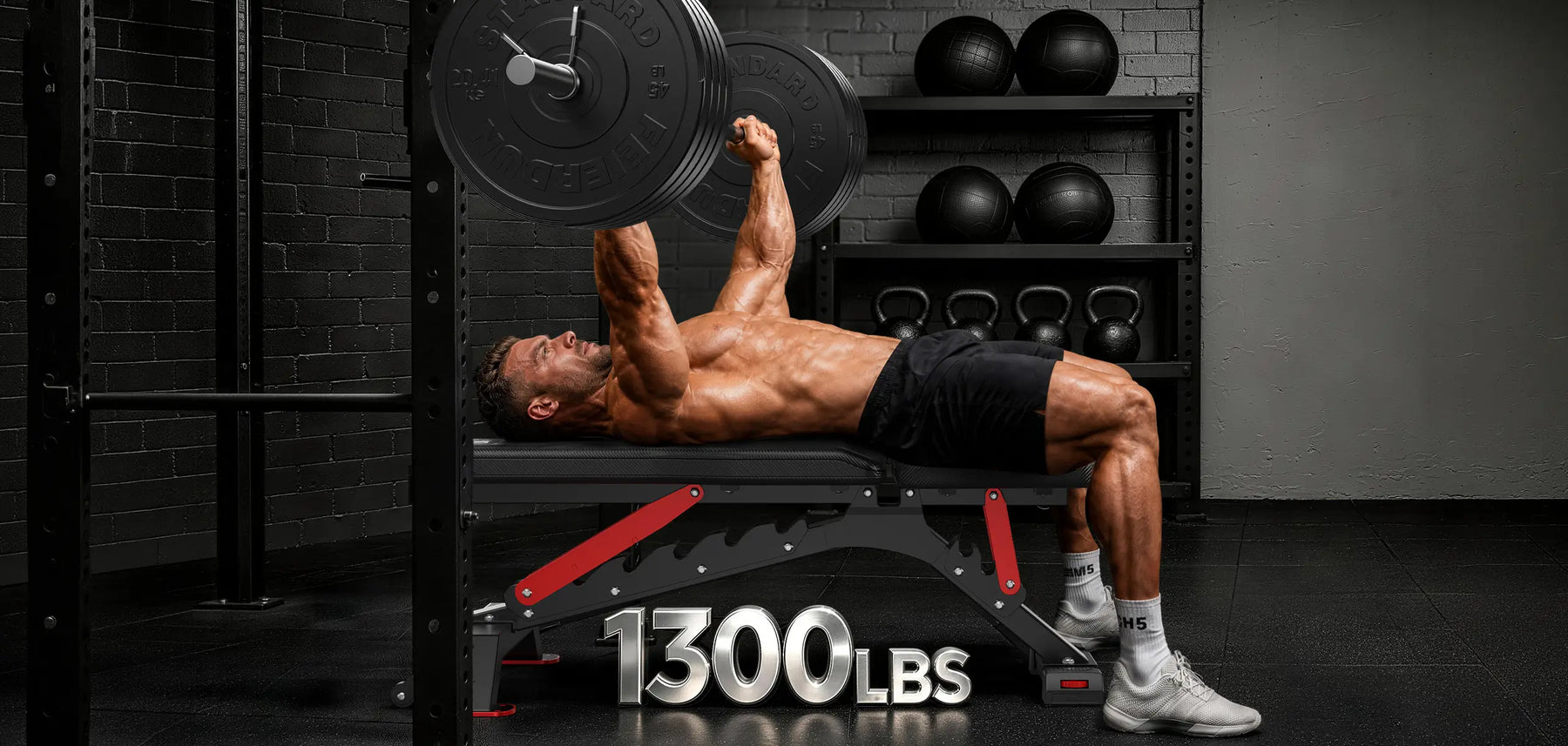 A shirtless man lies on a weight bench in a gym, holding a barbell overhead. The bench has a large '1300LBS' graphic overlay at the bottom.